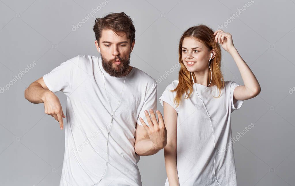 cheerful man and woman in headphones listening to music and dancing on gray background cropped view