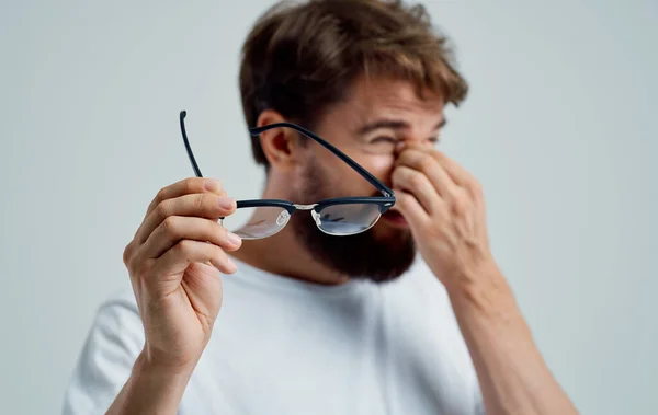 Mężczyzna z zwężonymi oczami trzyma okulary w dłoni na lekkich problemach z widzeniem w tle — Zdjęcie stockowe