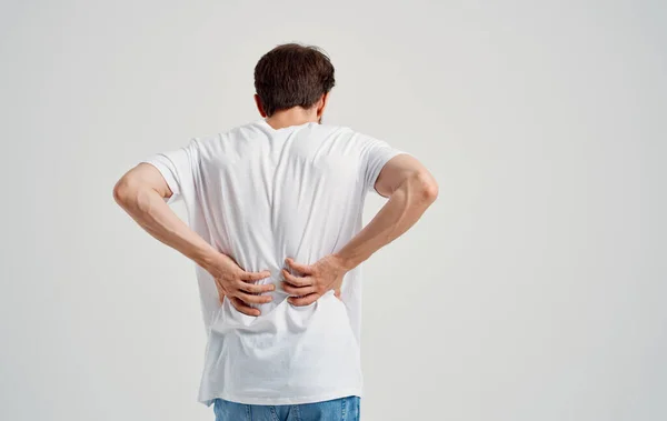 Hombre en camiseta blanca dolor de espalda osteocondrosis de la columna vertebral modelo vista posterior — Foto de Stock