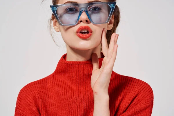 빨간 스웨터를 입고 파란 안경을 쓰고 밝은 배경 감정에 움푹 들어간 최신 여성 모델 — 스톡 사진