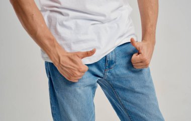 Kotlu ve tişörtlü bir adam kemerin altında başparmağını gösteriyor.