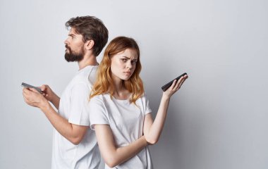 Beyaz tişörtlü kadın ve erkek ellerinde telefonla romantik iletişim teknolojisi.