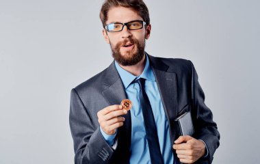 Ceketli bir iş adamı elinde bir kripto para tutuyor Bitcoin döviz kurları