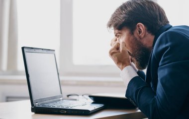 İş adamı, dizüstü bilgisayarlı iletişim bürosunun önünde takım elbiseli bir şekilde masasında.