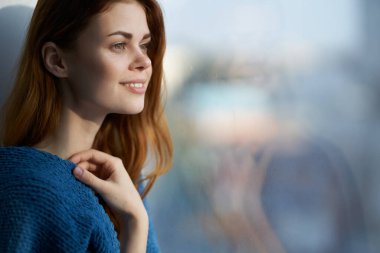 gülümseyen kadın pencerenin yanında bir battaniyeyle saklanıyor dinlenme sabahı güneşi