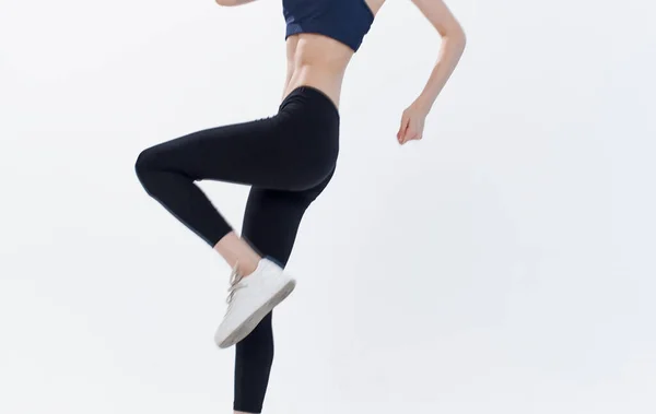 Energiegeladene Frau auf hellem Hintergrund springt in Sportkleidung — Stockfoto