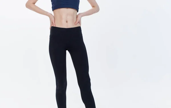 Tozluk ve tişört giyen sportif bir kadın arka planda fitness yapıyor. — Stok fotoğraf