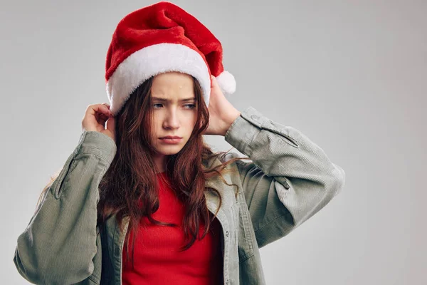 Fille dans une casquette de Noël avec un pompon sur un portrait de fond gris — Photo