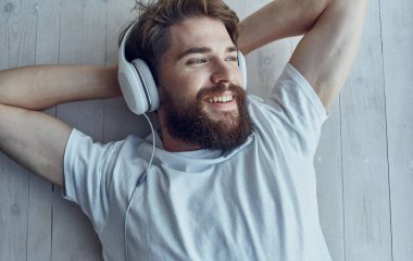 Kulaklıklı sakallı bir adam müzik dinliyor.