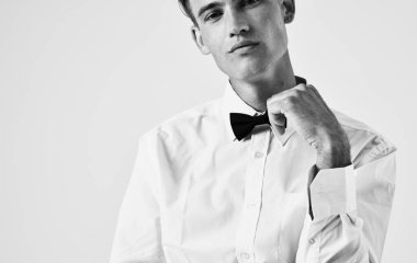 Açık arkaplan portresi üzerinde gömlek ve papyon takan yakışıklı bir adam.