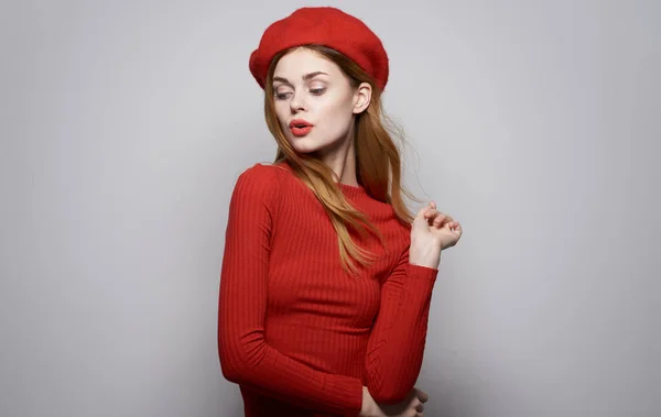 Mujer bonita en vestido rojo cosméticos elegante estilo emociones rojo sombrero gris fondo — Foto de Stock