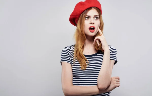 Joyeux modèle dans un chapeau rouge et dans un T-shirt rayé sur un fond clair émotions portrait — Photo