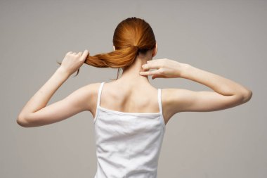 Kızıl saçlı kadın elleriyle kendine dokunuyor. Beyaz tişörtlü.