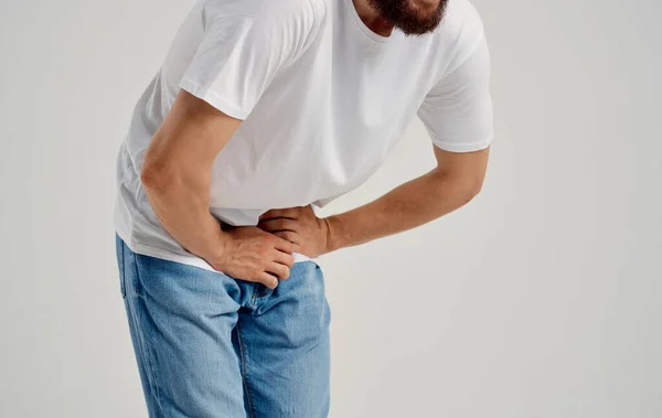 Man experiencing pain below the belt in the groin and jeans t-shirt model — Stock Image Man experiencing pain below the belt in the groin and jeans t-shirt model Royalty Free Stock Images