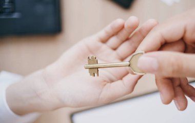 Anahtarı elden ele vermek ofis işi finans belgeleri masasında.