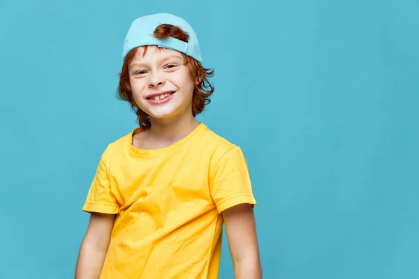 Radosny rudowłosy chłopiec z czapką na głowie żółty t-shirt dzieciństwo — Zdjęcie stockowe