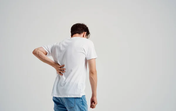 Hombre en camiseta blanca dolor de espalda osteocondrosis de la columna vertebral modelo vista posterior — Foto de Stock