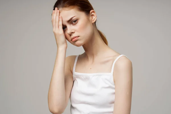 Mooie vrouw in wit t-shirt aanraken gezicht met handen op grijze achtergrond gezondheidsproblemen hoofdpijn — Stockfoto