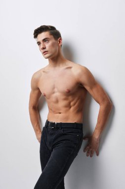 Spor pantolonlu adam duvarın yanında duruyor.