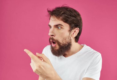 Pembe arka planda sakallı bir adam elleri asabiyet duygusallık modeliyle el kol hareketleri yapar.