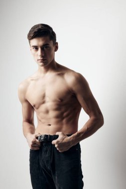 Spor figürlü ve pantolonlu bir adam arka planda fitness kaslarının görüntüsünü kırptı.