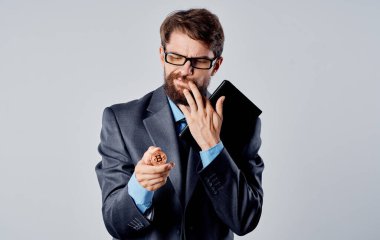 Ellerinde bozuk para ve şaşkın bakışları olan bir iş adamı Bitcoin kripto para ile el kol gezer.