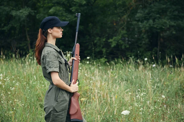 그의 앞에 총을 들고 자연에 있는 여자는 검은 모자, 녹색 작업복 — 스톡 사진