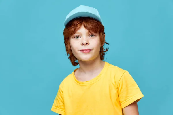 Fiú vörös hajjal portré egy fiúról kék sapkában sárga pólóban — Stock Fotó