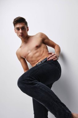 Pantolon giymiş, bacağı kalkık ve gövdesi çıplak bir adam.