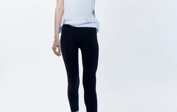 Жінка в приміщенні на світлому фоні і чорні легінси в білій футболці — стокове фото
