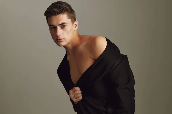 A young guy in a jacket with bare shoulders leaned to the side — Stock Photo, Image