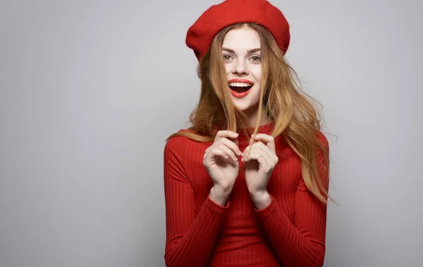 Mooie vrouw in rode trui en hoed cosmetica model grijze achtergrond — Stockfoto