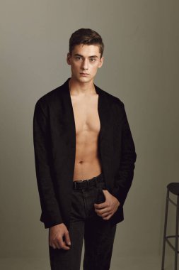 Genç adam, modaya uygun siyah ceketli çekici bej arkaplan.