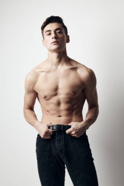 Çıplak gövdeli ve kot pantolonlu bir adam arka planda kırpılmış.