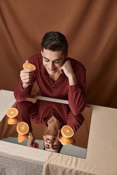 Handsome man at the table with oranges on the mirror top view — Stock Photo, Image