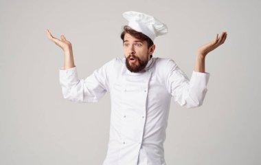 Açık renk elbiseli şef başlığıyla el kol hareketi yapıyor.