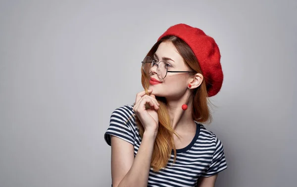 Красивая дама в футболке жестикулируя в очках рук модель красной шляпы — стоковое фото