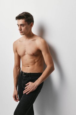 Siyah pantolonlu bir adam kırpık manzaralı bir duvarın karşısında duruyor.