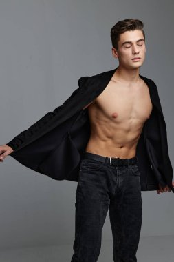 Düğmeleri iliklenmemiş gömlekli ve pantolonlu genç bir adam ellerini yana atıyor.