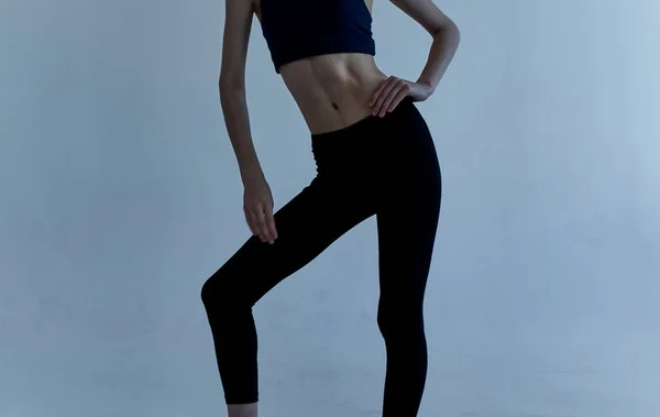Sportowa kobieta w legginsach i T-shircie zajmuje się fitness na jasnym tle — Zdjęcie stockowe