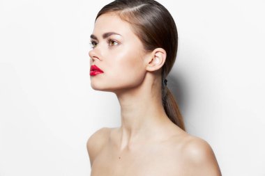 Genç, çıplak omuzlu çekici bir kadın. Yakın çekimde, açık tenli, kırmızı dudaklı.