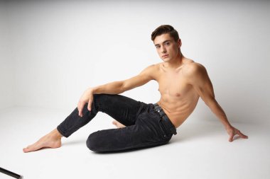 Çıplak vücutlu bir erkek stüdyoda otururken izole bir arka plan modeli gibi görünüyor.