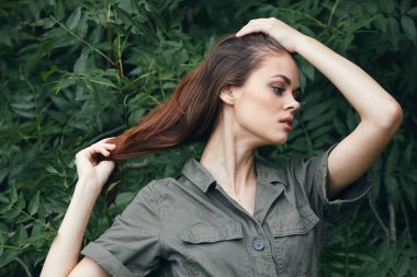 Tayga ormanındaki yeşil yapraklarda cepleri ve makyajı olan esmer kadın gömleği. 