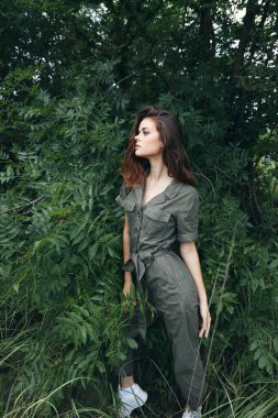 Ormandaki kadın Çalılıkların yanındaki yeşil tulumlu yaz manzaralı