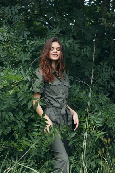 Ormanda yeşil tulumlu, gözleri kapalı bir kadın doğa yolculuğu yapıyor. — Stok fotoğraf