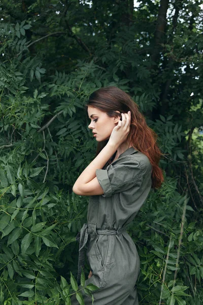 Woman in the forest Touches the hair on the head and the landscape green jumpsuit nature