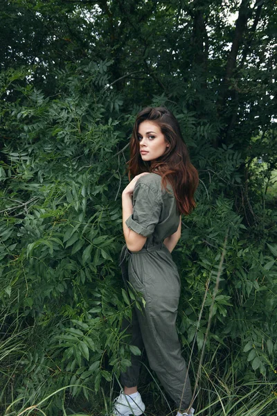 Woman in forest In Green Overalls near the Bushes fresh air