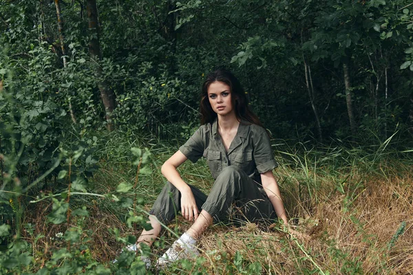 Bella donna in tuta si siede su erba secca nella foresta naturale — Foto Stock