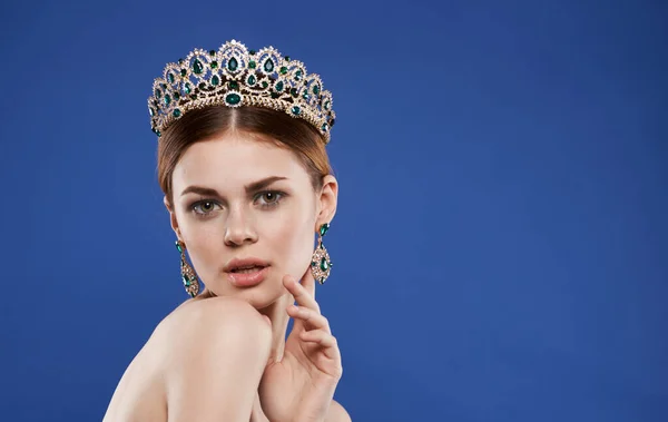 Bella donna con un diadema sulla testa su uno sfondo blu bellezza regina con orecchini modello di trucco — Foto Stock