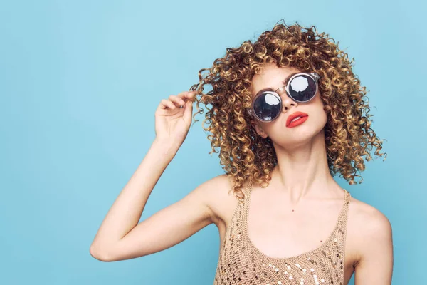 Vrouw rood lippen krullend haar zonnebril aantrekkelijk glamour look blauw achtergrond — Stockfoto